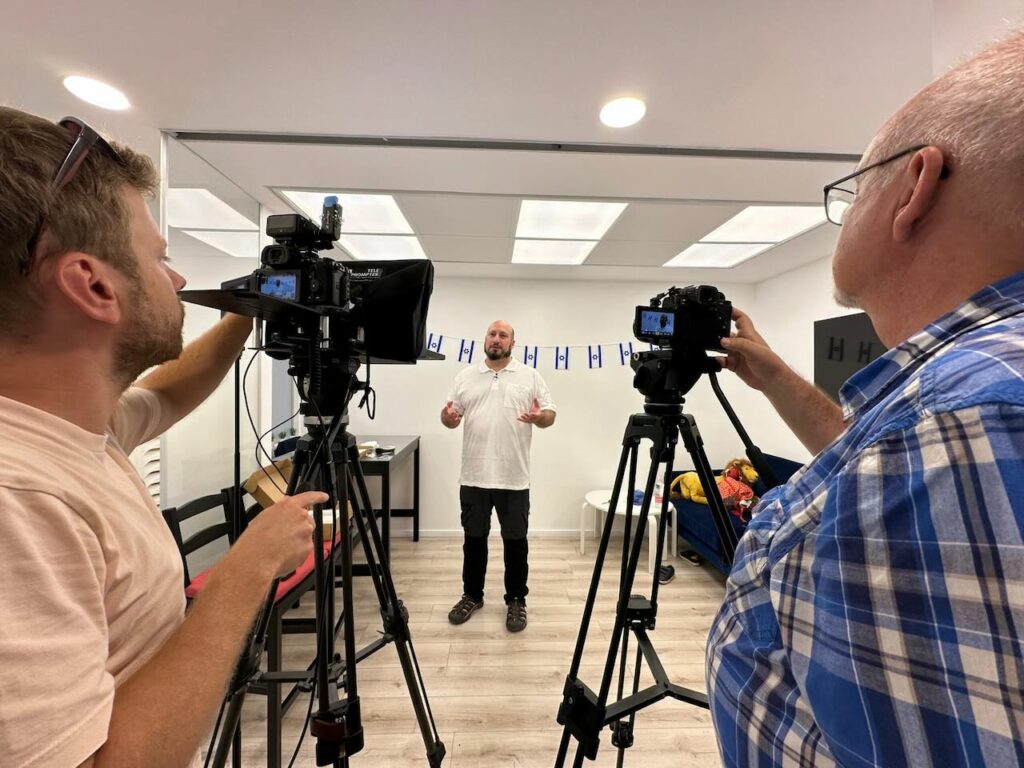 a group of men taking a picture of a man standing in front of a camera